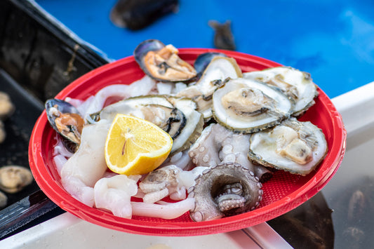 a disposable red plate with raw seafood and a wedge of lemon