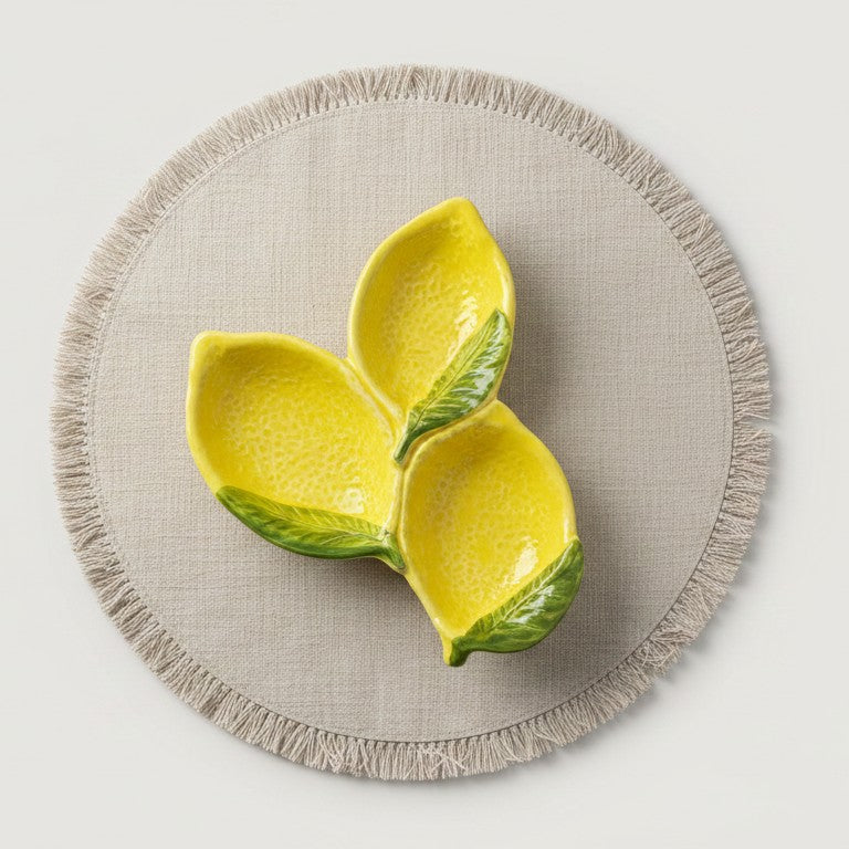Yellow ceramic lemon-shaped bowl on a beige placemat with a light gray background