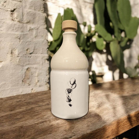 ceramic bottle with a balloon design on wooden surface with a brick wall and cactus plants in the background