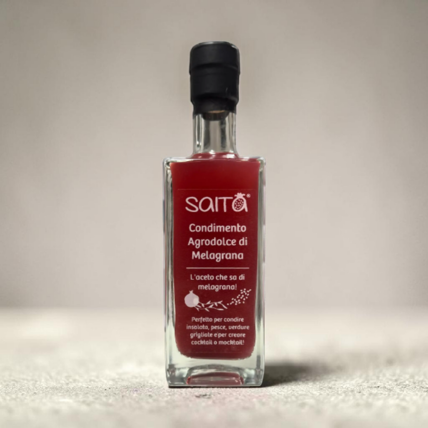 Bottle of Saita agrodolce di melagrana on a neutral background