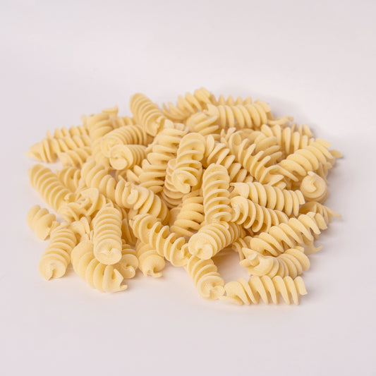 uncooked pasta fusilli on a white background
