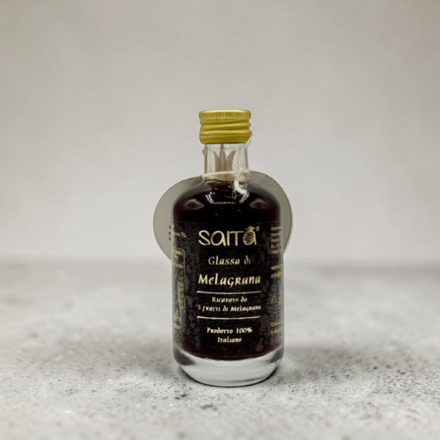 Small bottle of Saita Glassa di Melagrana on a textured surface with a light background