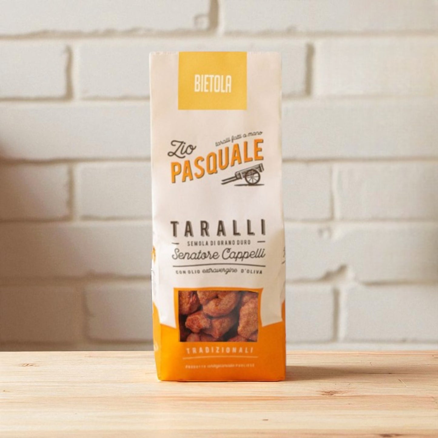 A pack of Zio Pasquale Taralli on a wooden surface with a white stone wall background