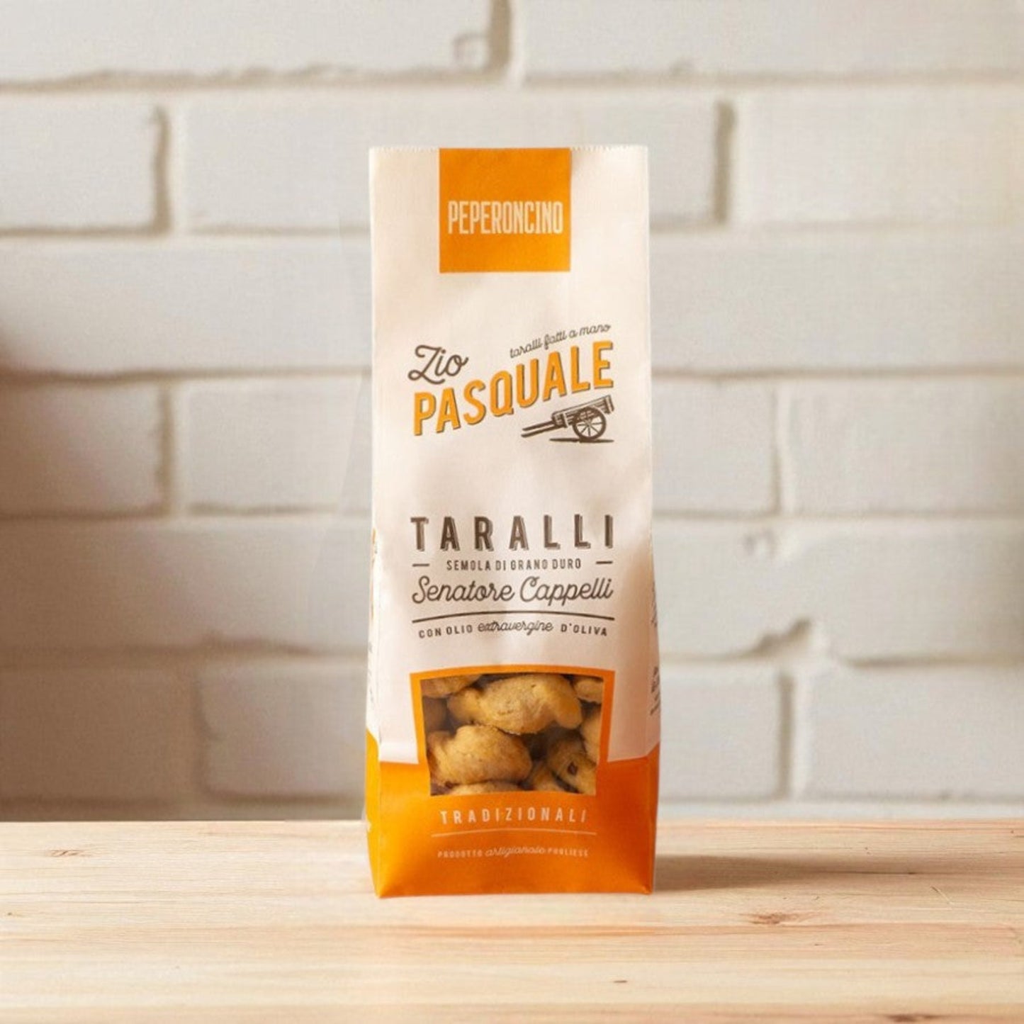 Packaging of Zio Pasquale Taralli on a wooden surface with a white brick wall background.