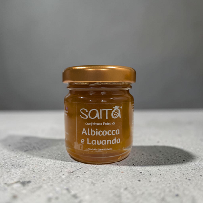 Jar of Saità confettura Extra d'Albicocca e Lavanda on a gray surface with a gray background