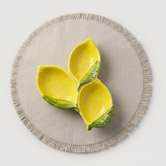 Yellow ceramic lemon-shaped bowl on a beige placemat with a light gray background