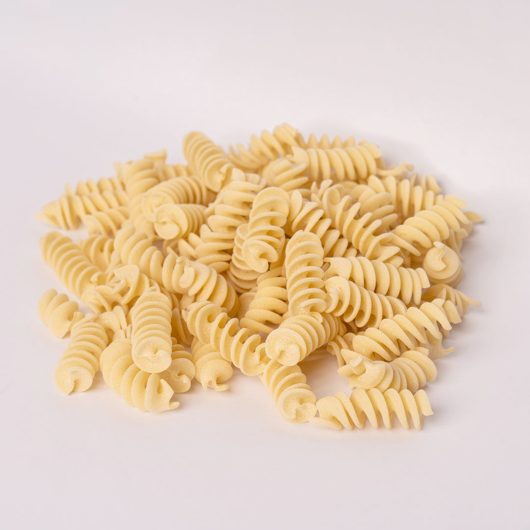 uncooked pasta fusilli on a white background
