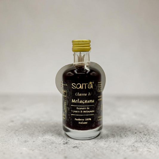 Small bottle of Saita Glassa di Melagrana on a textured surface with a light background