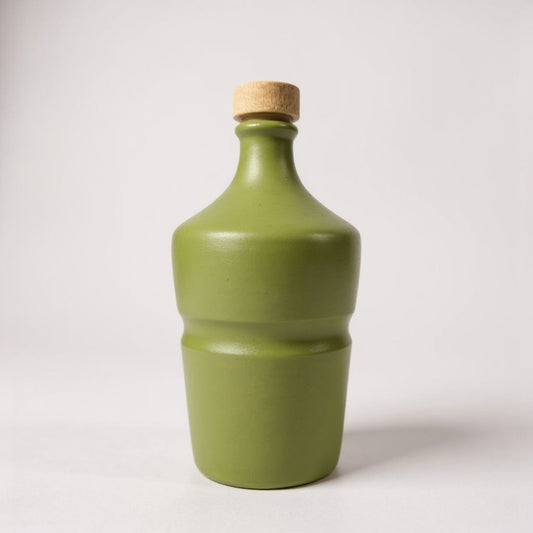 Green ceramic bottle with cork stopper on a white background
