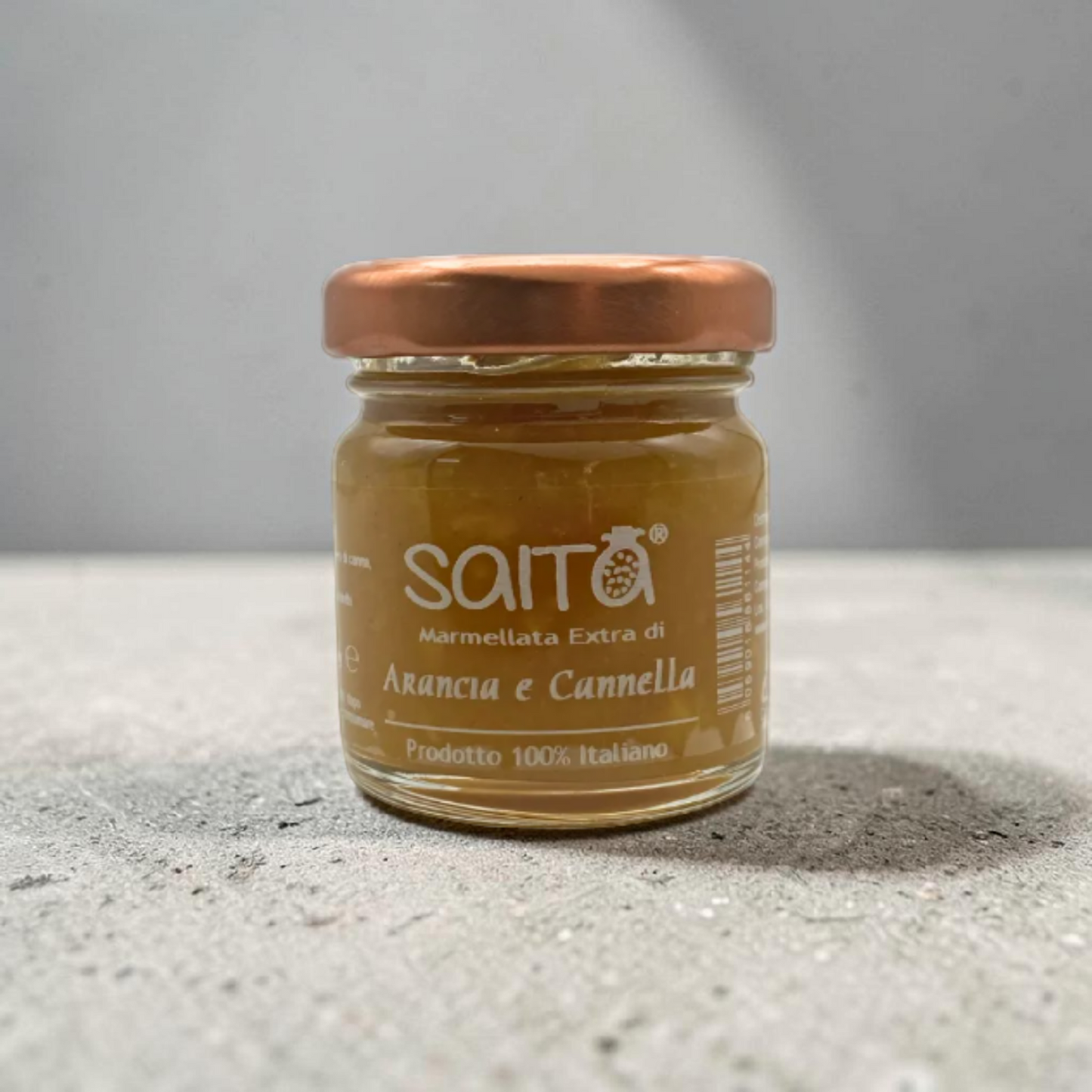 Jar of Saita marmellata on a gray surface with a gray background