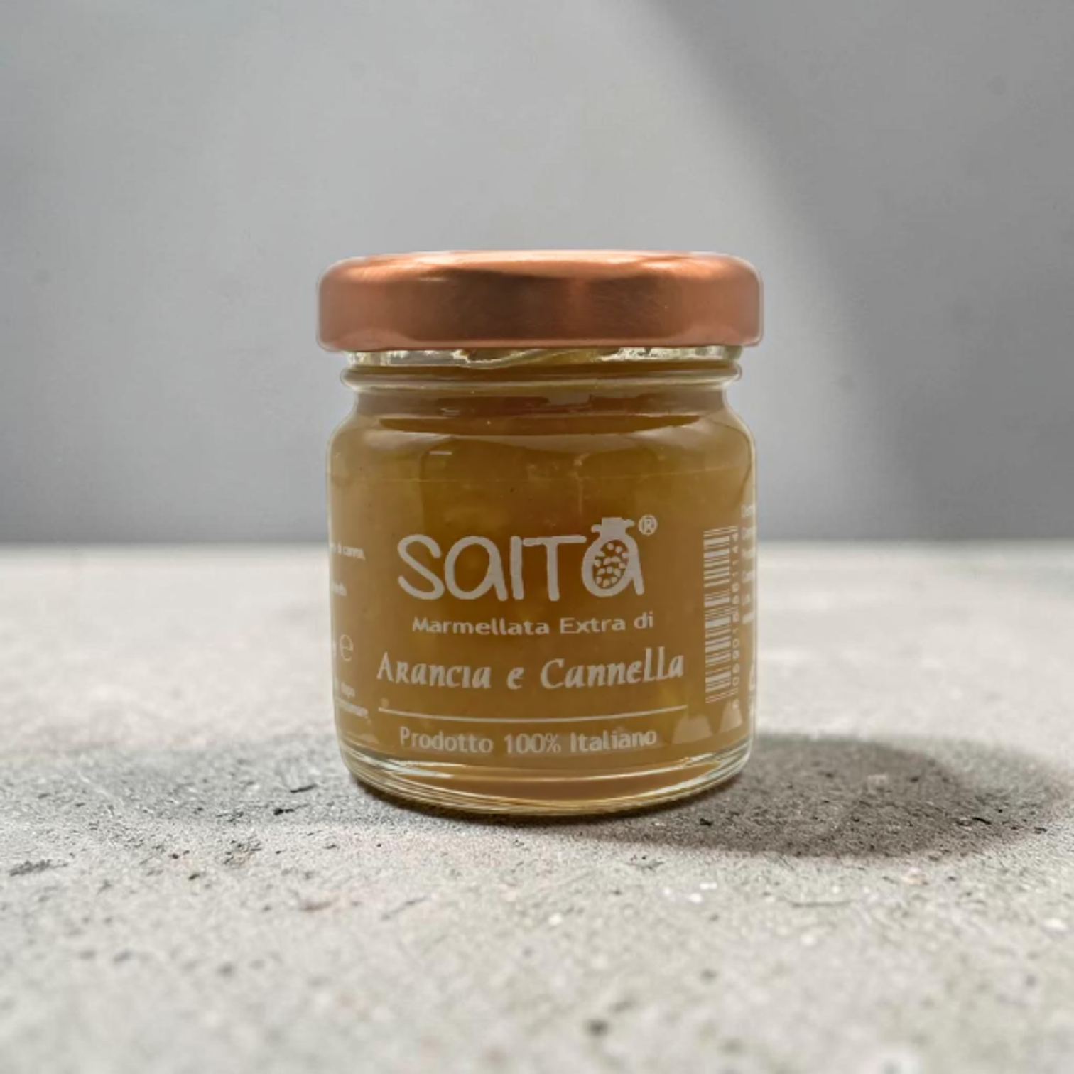 Jar of Saita marmellata on a gray surface with a gray background