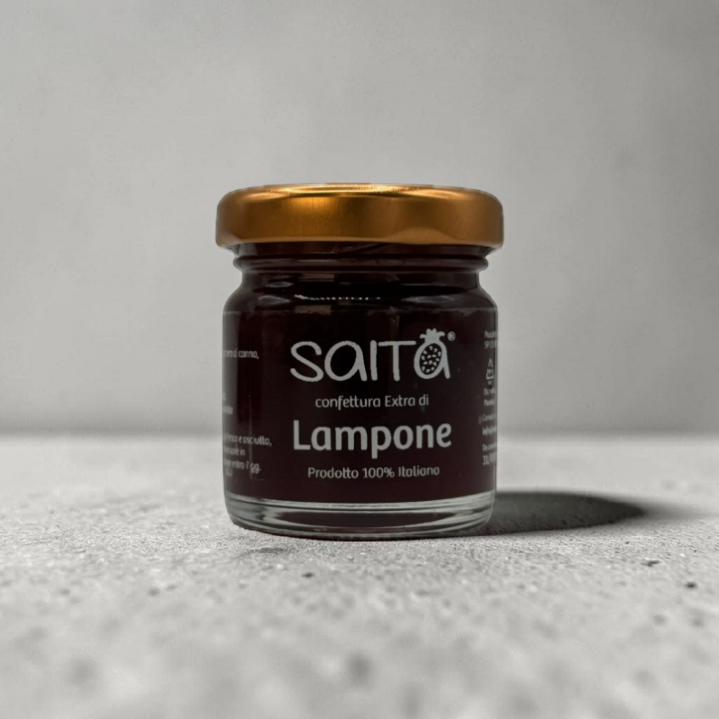 Jar of Saita  lampone jam on a gray surface with a neutral background