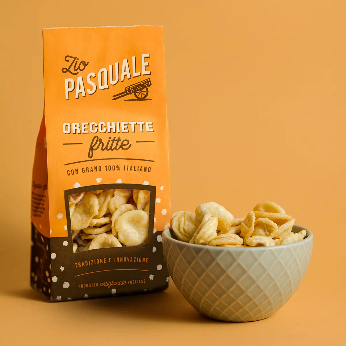 Packaged fried pasta snack with a bowl of pasta on an orange background