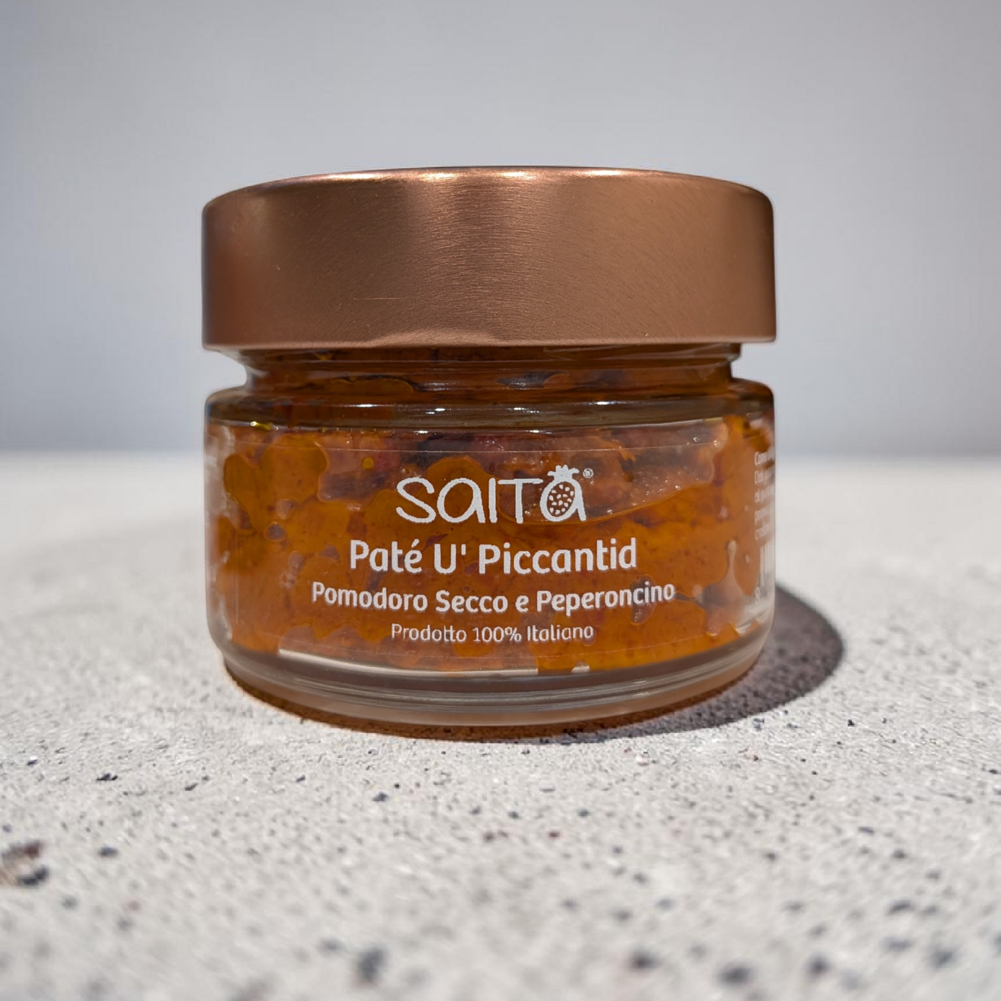 Jar of Saitá Paté U' Piccantid on a grey surface with a grey background