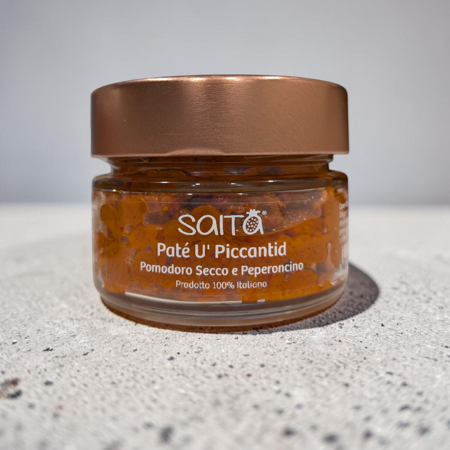 Jar of Saitá Paté U' Piccantid on a grey surface with a grey background