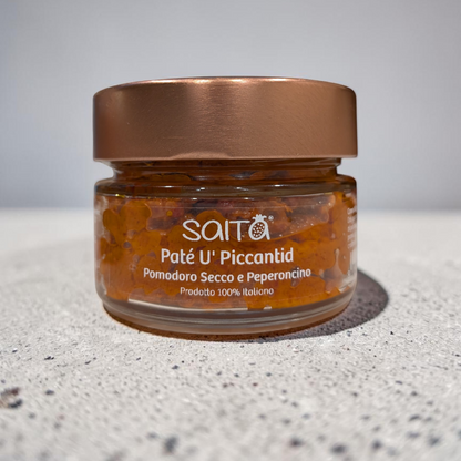 Jar of Saitá Paté U' Piccantid on a grey surface with a grey background