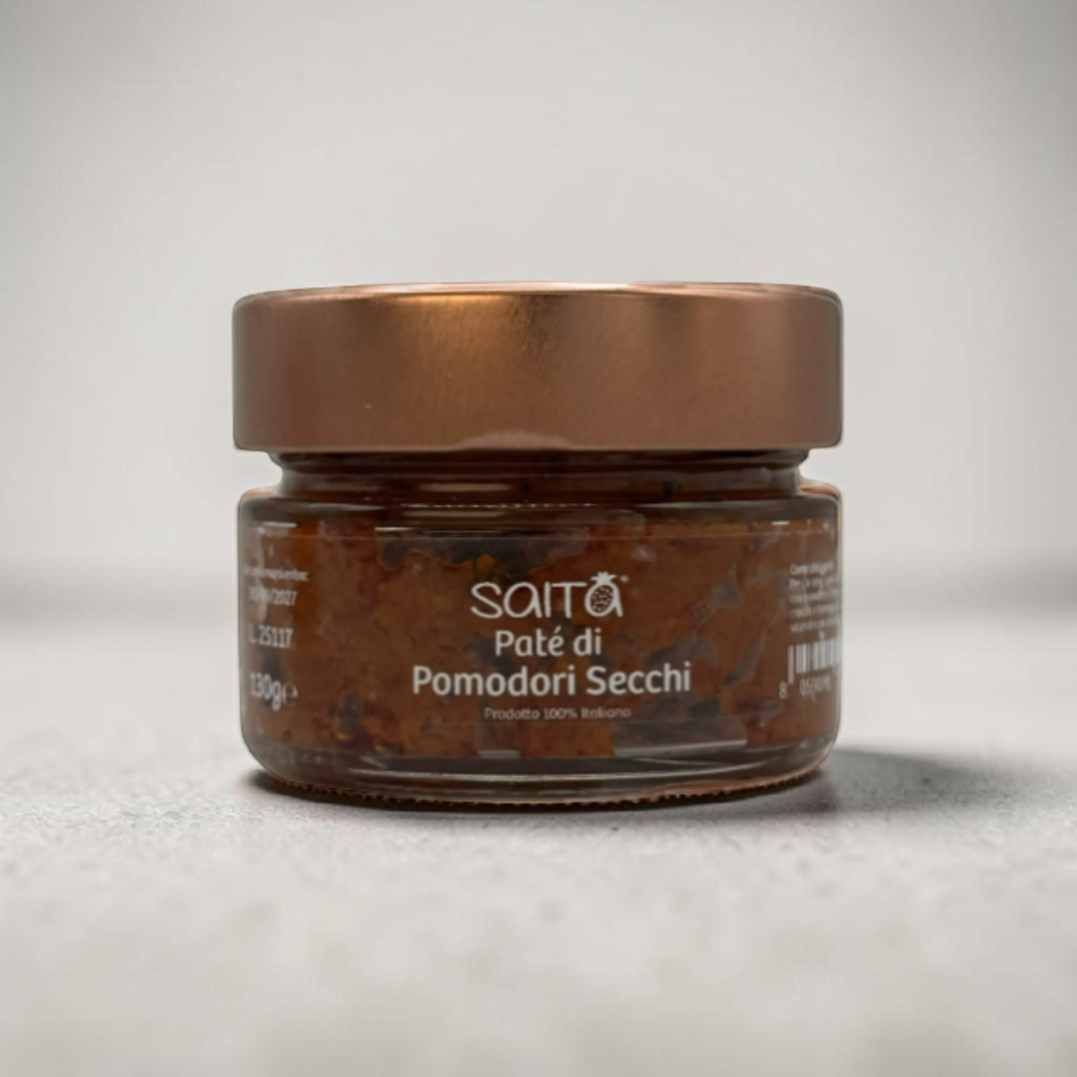 Jar of Saità tomato pate di pomodori secchi with a bronze lid on a light grey background
