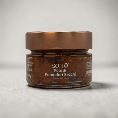 Jar of Saità tomato pate di pomodori secchi with a bronze lid on a light grey background