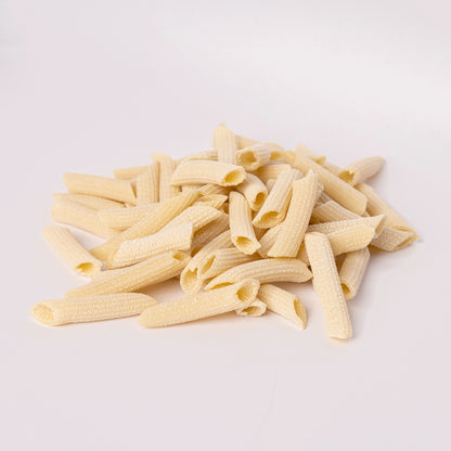 Pile of uncooked penne pasta on a light gray background