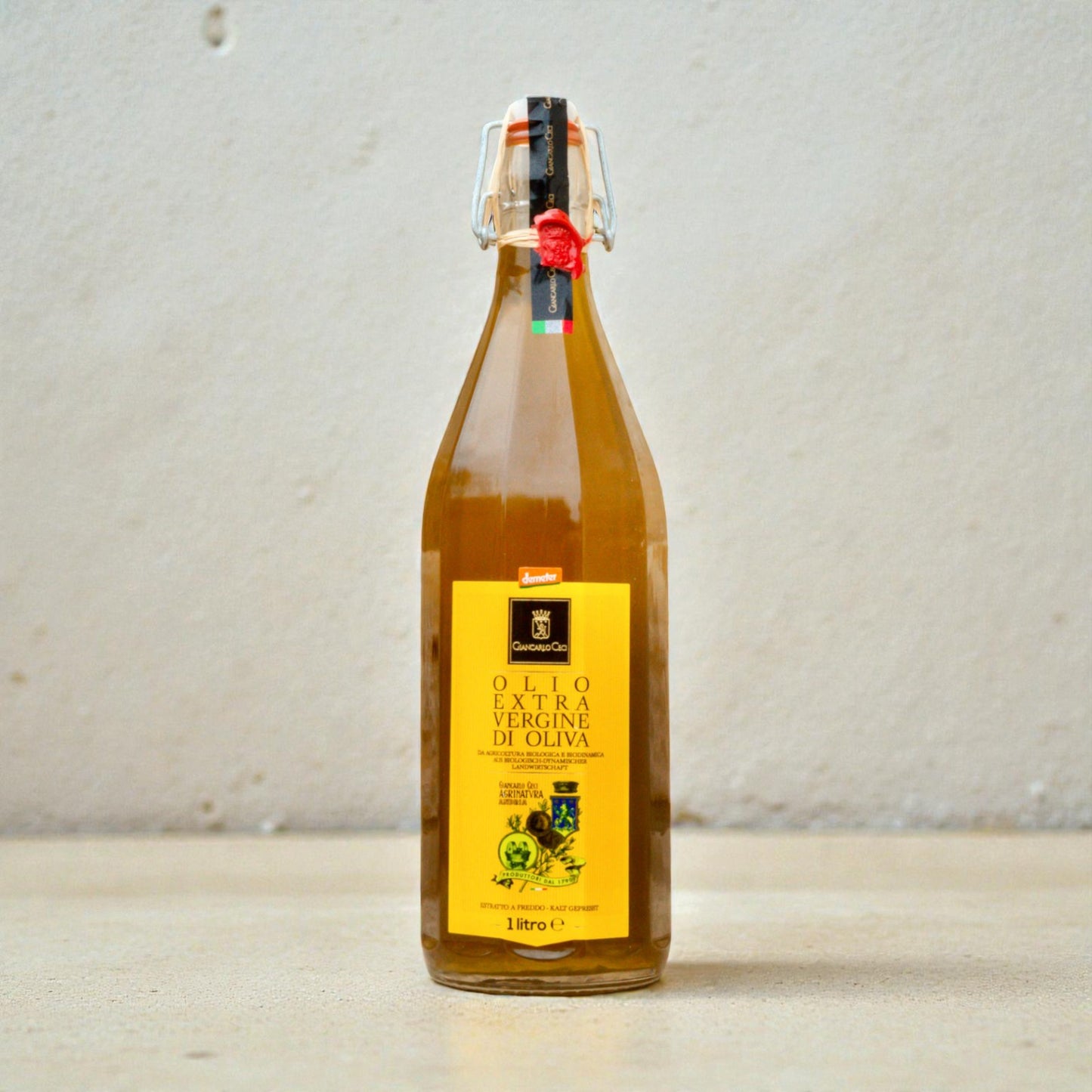glass bottle of olive oil on a pale beige surface with a white plaster wall behind