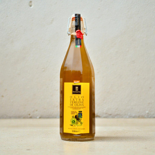 glass bottle of olive oil on a pale beige surface with a white plaster wall behind