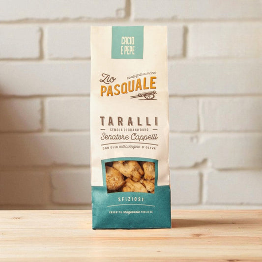 Packaging of Zio Pasquale Taralli on a wooden surface with a white stone wall background