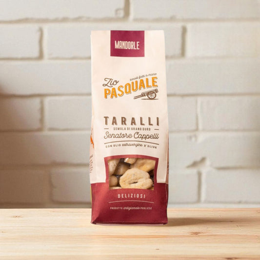 Packaging of Taralli snacks on a wooden surface and white stone wall background