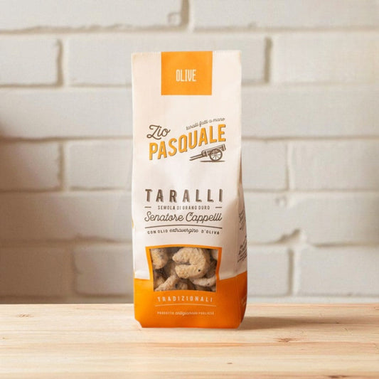 Zio Pasquale Taralli package on a wooden surface with a white stone wall background